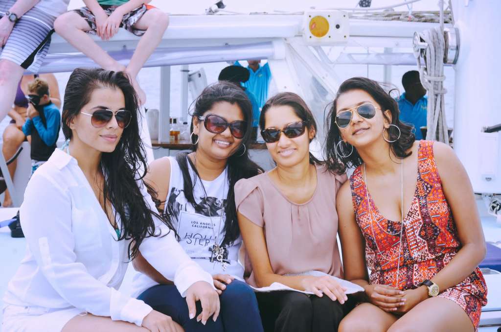 Four friends smiling together while seated on a boat.