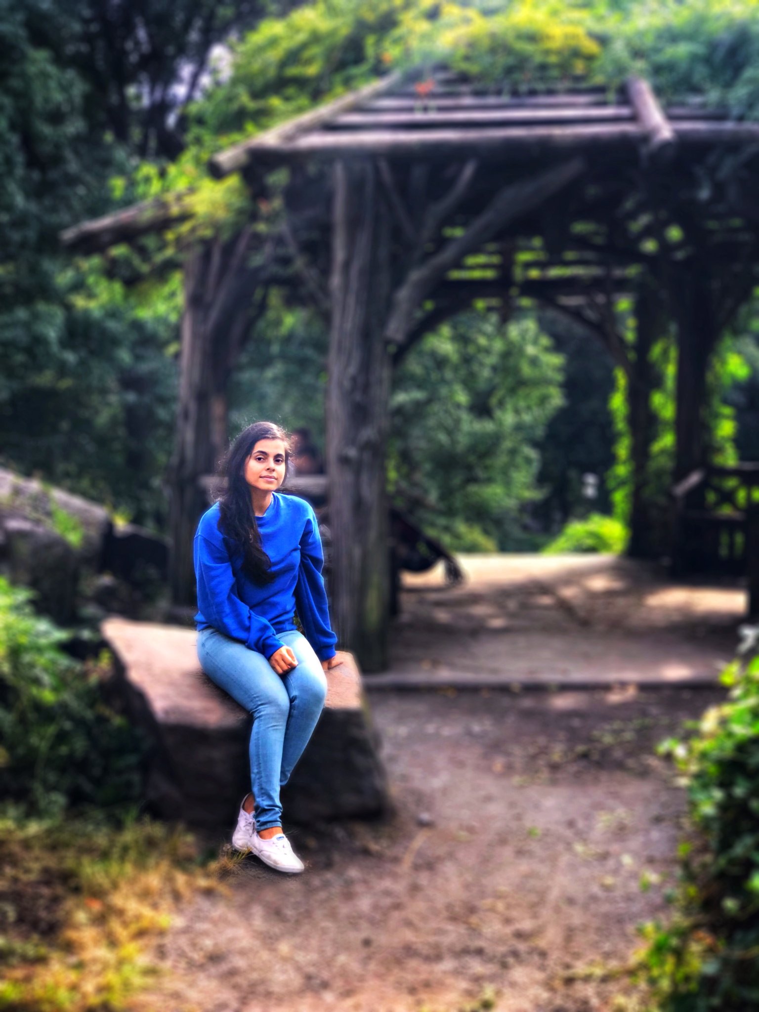 Woman in blue top and jeans sitting peacefully in garden setting